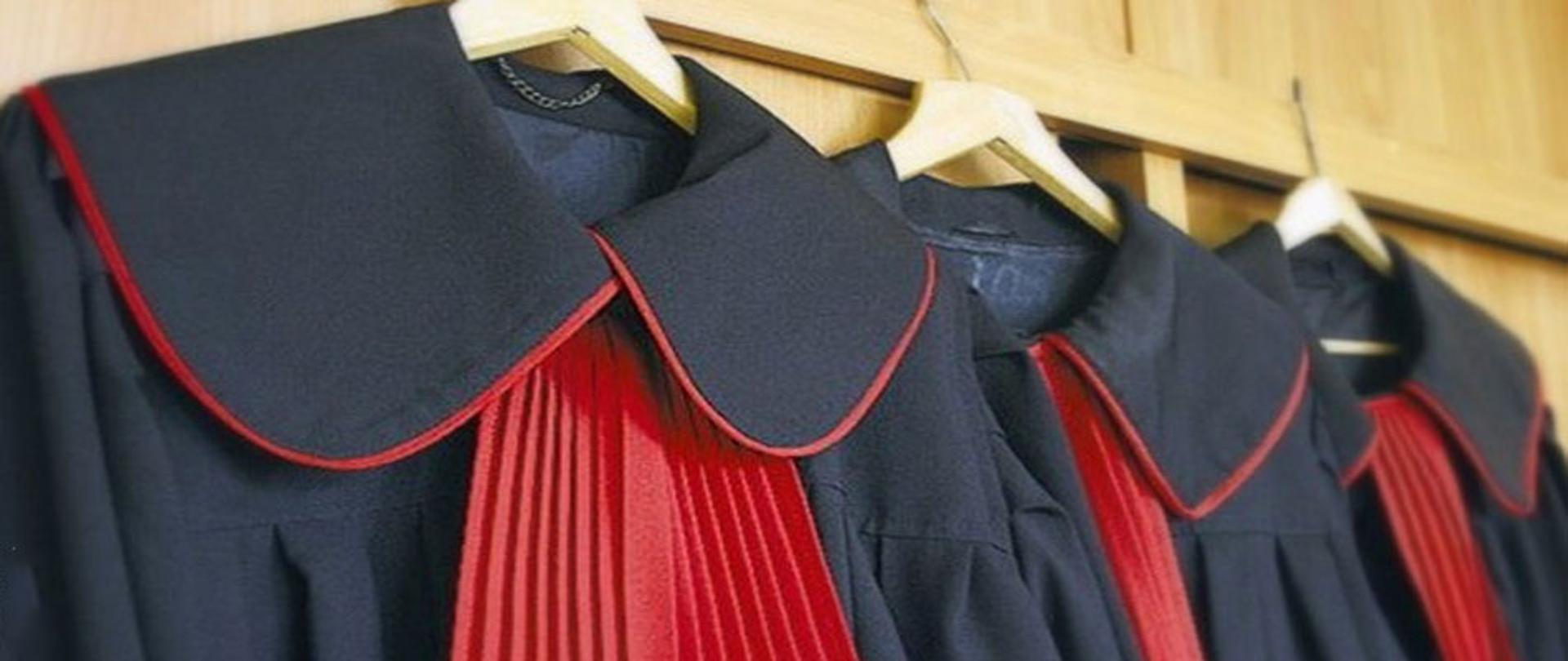 Trzy wiszące togi prokuratorskie