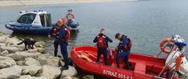 Widok z przodu. Widok z przodu. Łodzie motorowe przy brzegu jeziora. Po lewej stronie łódź motorowa Policji, po prawej stronie łódź motorowa PSP. Na pierwszym planie strażacy PSP przygotowujący się do rozpoczęcia patrolu. W tle widoczna zapora wodna.
