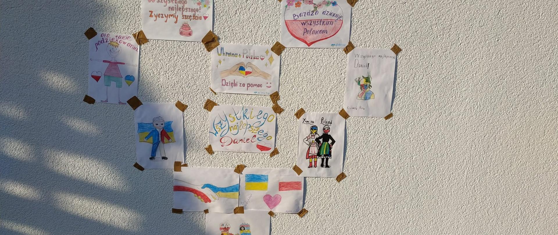 Serce wykonane z laurek dzieci, który uciekły przed konfliktem zbrojnym w Ukrainie. Serce przyklejone taśmą klejącą do elewacji remizy OSP.