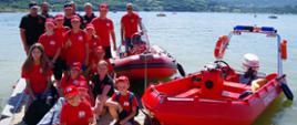 Zdjęcie grupowe. Na pierwszym panie członkowie MDP i ratownicy na pomoście. Po prawej stronie dwie łodzie ratownicze. W tle - jezioro.