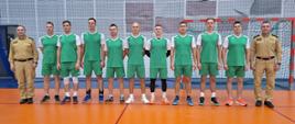 Strażacy stoją na sali sportowej podczas turnieju w piłce siatkowej
