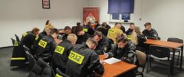 Na zdjęciu widoczni są strażacy-ochotnicy podczas teoretycznego egzaminu szkolenia podstawowego strażaków ratowników ochotniczej straży pożarnej.