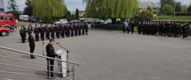 Zdjęcie przedstawia strażaków, którzy stoją na placu przed komendą podczas uroczystości obchodów dnia strażaka. 