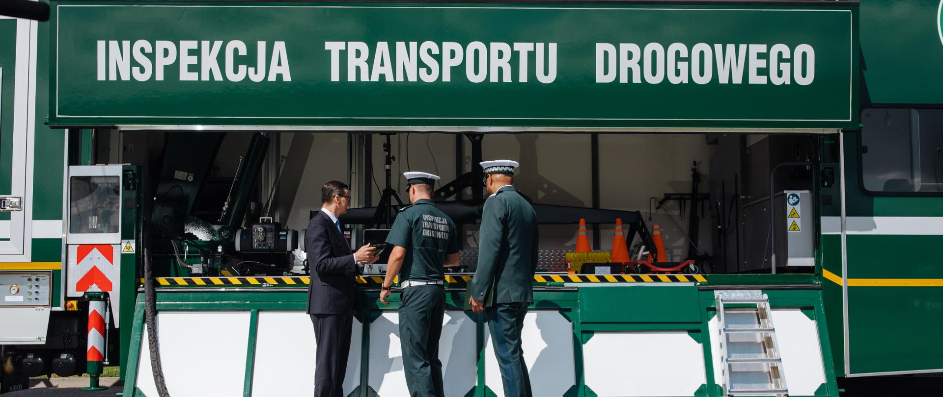 Premier stoi przy samochodzie Inspekcji Transportu Drogowego.