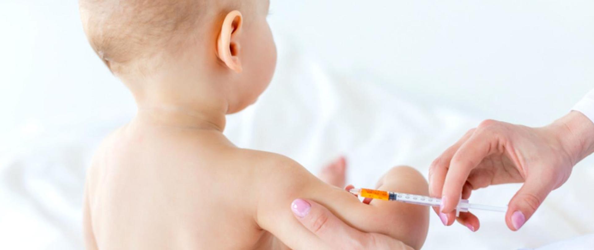 Dziecko obrócone tyłem na jasnym tle i ręce ze strzykawką . Szczepienie