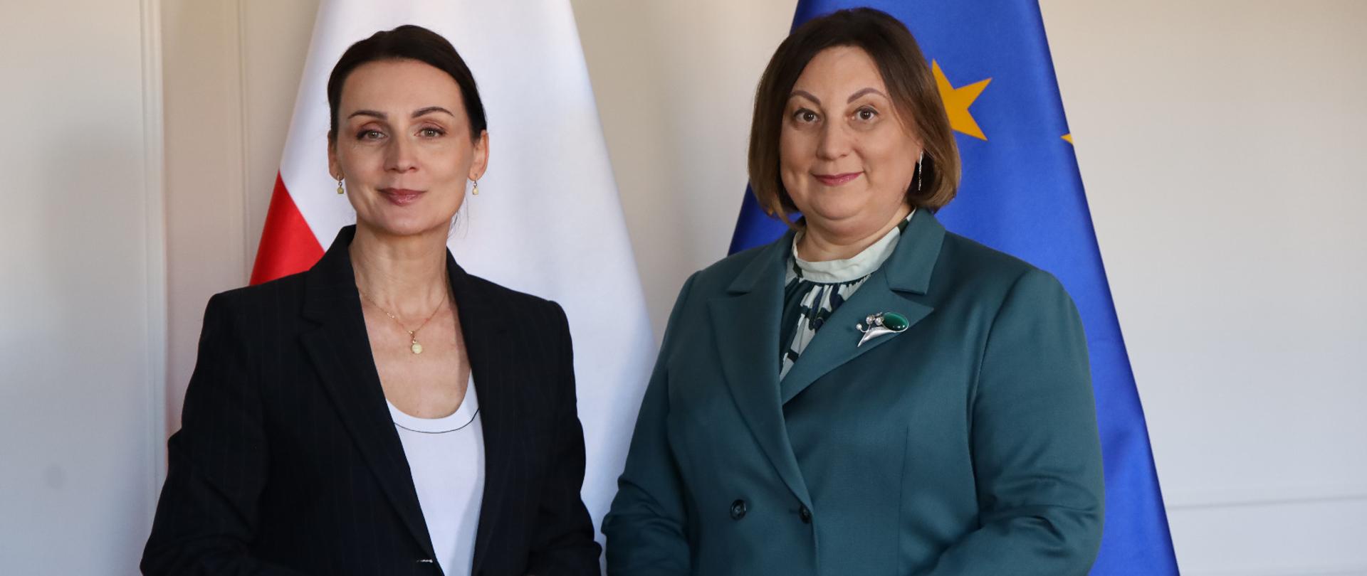 dwie kobiety pozują do zdjęcia na tle flagi Polski i UE