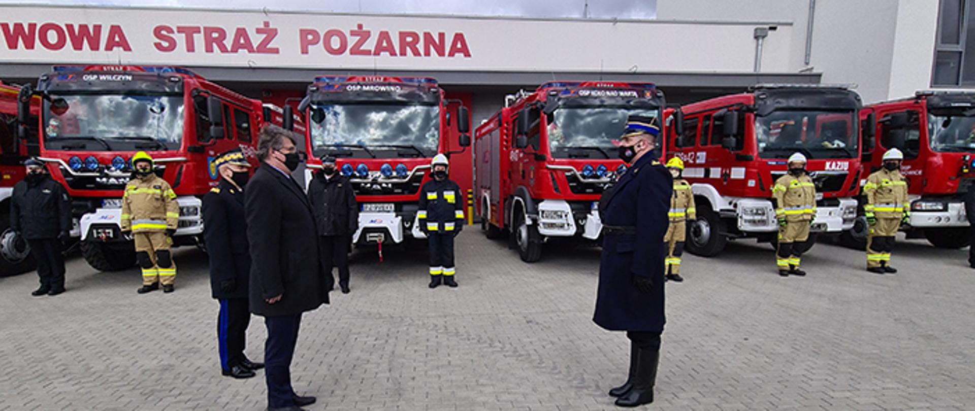 Powitanie ministra Macieja Wąsika oraz komendanta głównego nadbrygadiera Andrzeja Bartkowiaka. W tle przekazywane na uroczystości samochody pożarnicze oraz grraże nowo wybudowanej komendy we Wrześni