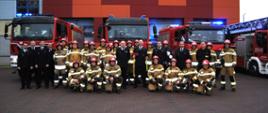 zdjęcie grupowe na tle samochodów pożarniczych.