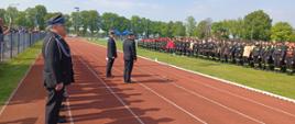 Na zdjęciu przedstawiciele władz OSP wraz z Komendantem Powiatowym PSP w Wolsztynie. Zdjęcie wykonane na stadionie miejskim. Słoneczny dzień, bezchmurne niebo. Trwa przemowa przed rozpoczęciem zawodów,