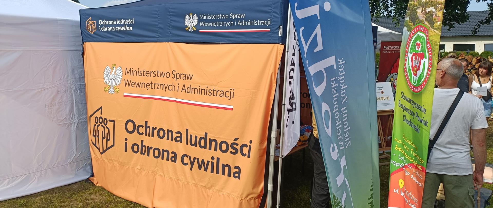 Zdjęcie przedstawia strażaków i uczestników podczas Akademii Ochrony Ludności i Obrony Cywilnej w miejscowości Rataje.
W tle plac i tereny zielone.
