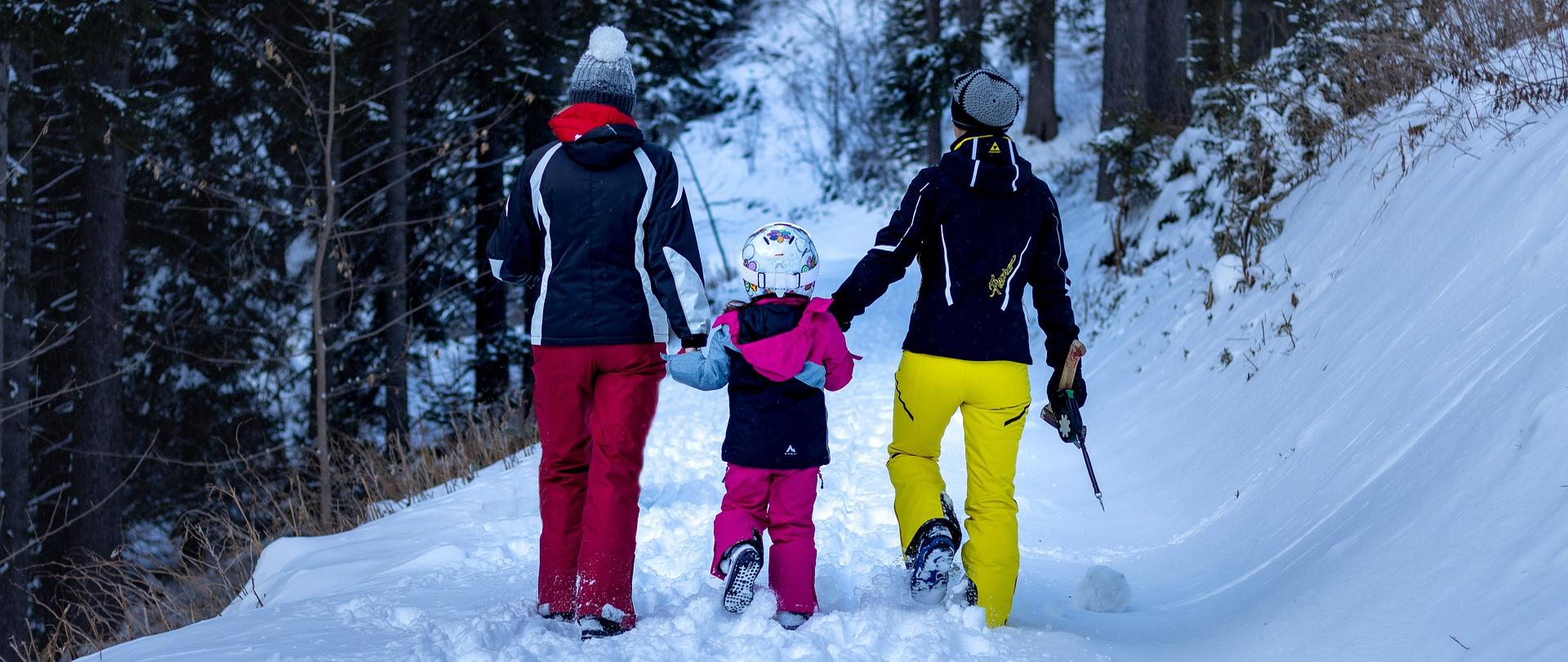 Przedstawiono rodzinę ubraną w zimową odzież podczas spaceru