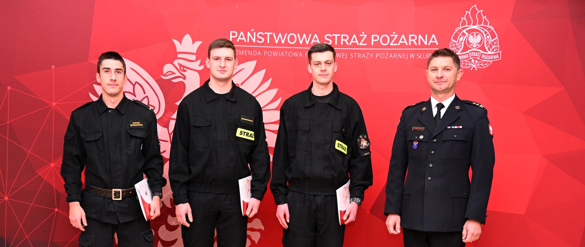 Na ściance awansowani trzech strażacy w obecności Komendanta Powiatowego