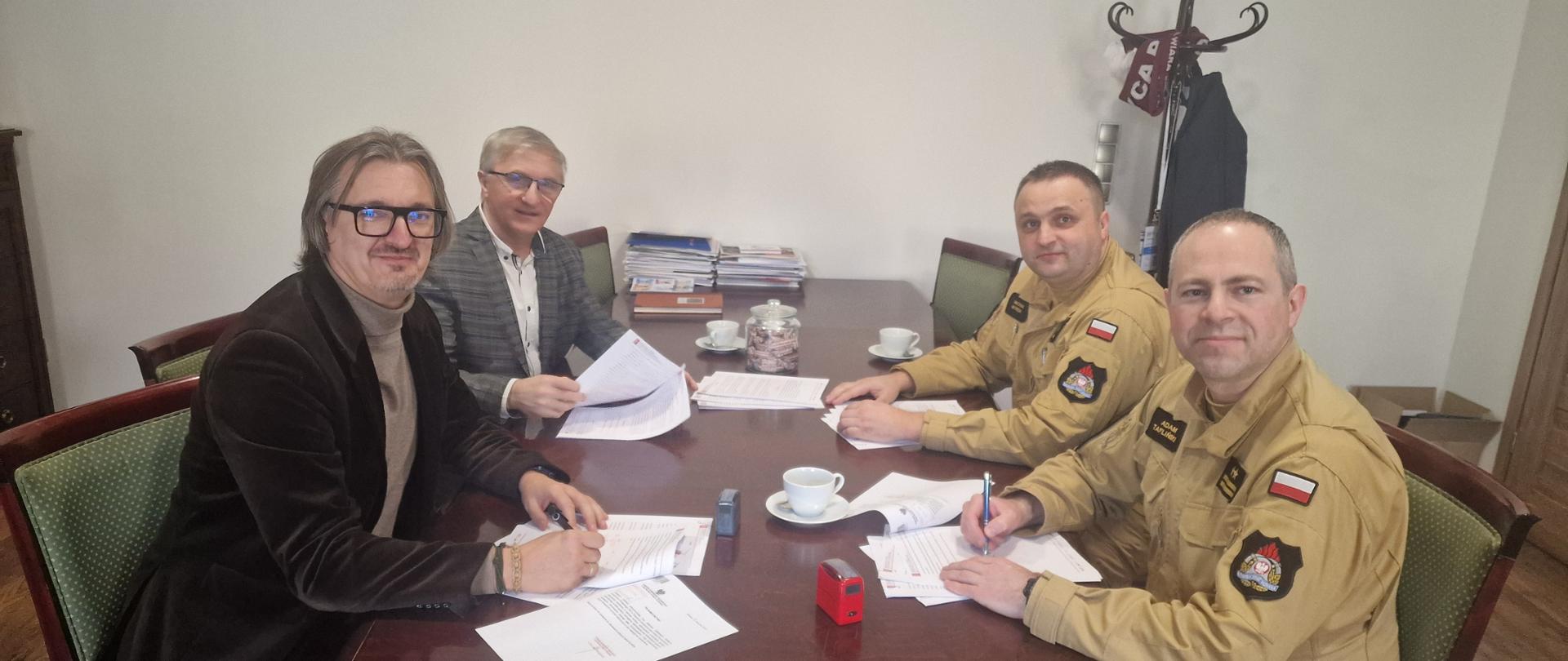 Burmistrz Miasta i Gminy Pelplin wraz z Sekretarzem Miasta i Gminy Pelplin oraz Zastępca Komendanta Powiatowego Państwowej Straży Pożarnej w Tczewie wraz z Naczelnikiem Wydziału Operacyjno Szkoleniowego KP PSP Tczew podczas podpisania porozumień dotyczących współpracy w zakresie montażu, wykorzystania i utrzymania sprzętu wchodzącego w skład systemu ostrzegania i alarmowania oraz infrastruktury systemu ostrzegania i alarmowania.