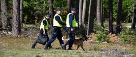 Zdjęcie przedstawia funkcjonariuszy Policji wraz z psem poszukujących podpalacza w trakcie ćwiczeń powiatowych 