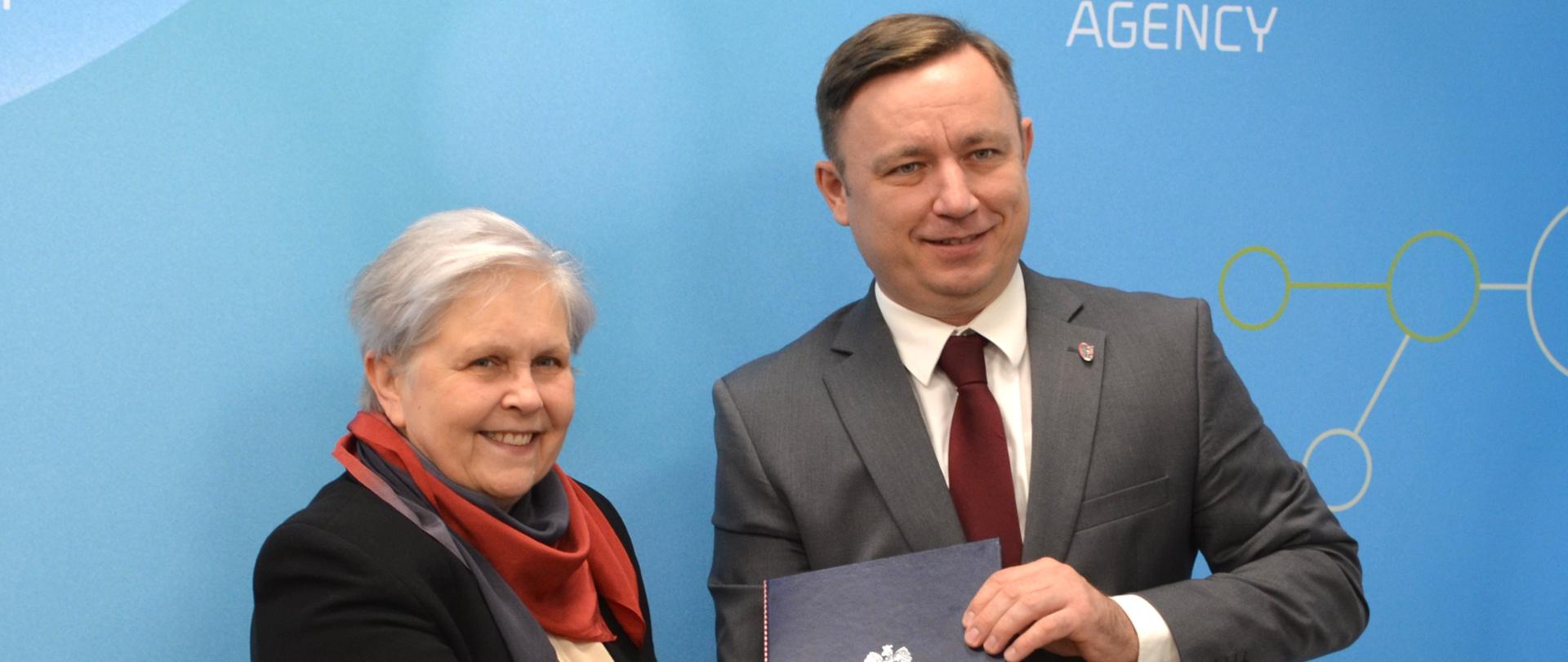 Elżbieta Andrukiewicz from the National Institute of Telecommunications receives the document from the President of the National Atomic Energy Agency, Andrzej Głowacki.