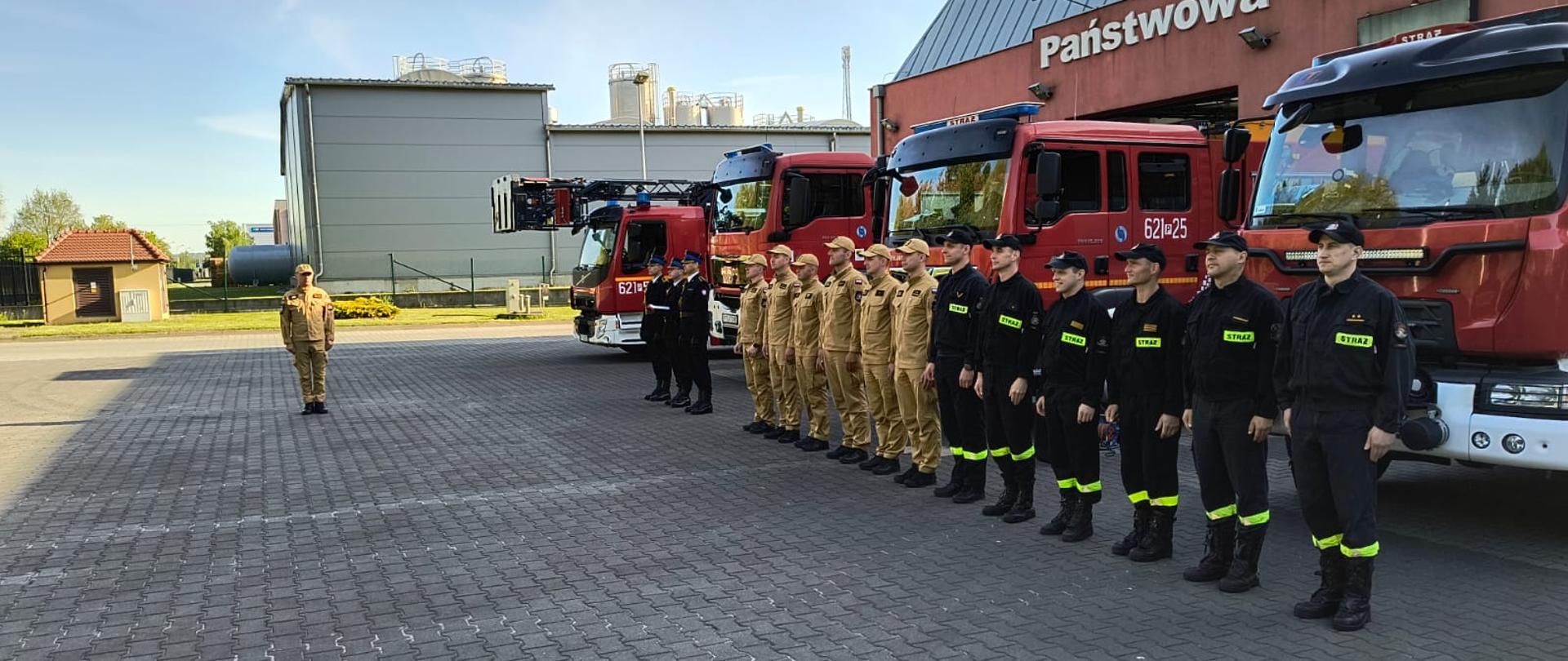 Strażacy stoją podczas uroczystej zbiórki z okazji narodowego święta flagi państwowej. 