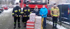 Strażacy wraz z organizatorami akcji "Stalowowolska paczka pomocy - samotny, ale nie sam" i darami na tle samochodu pożarniczego