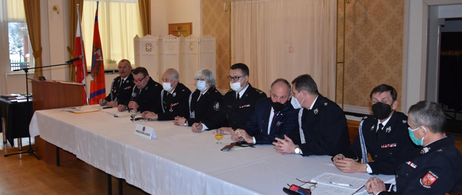 Wybrani delegaci siedzą przy stole prezydialnym. 