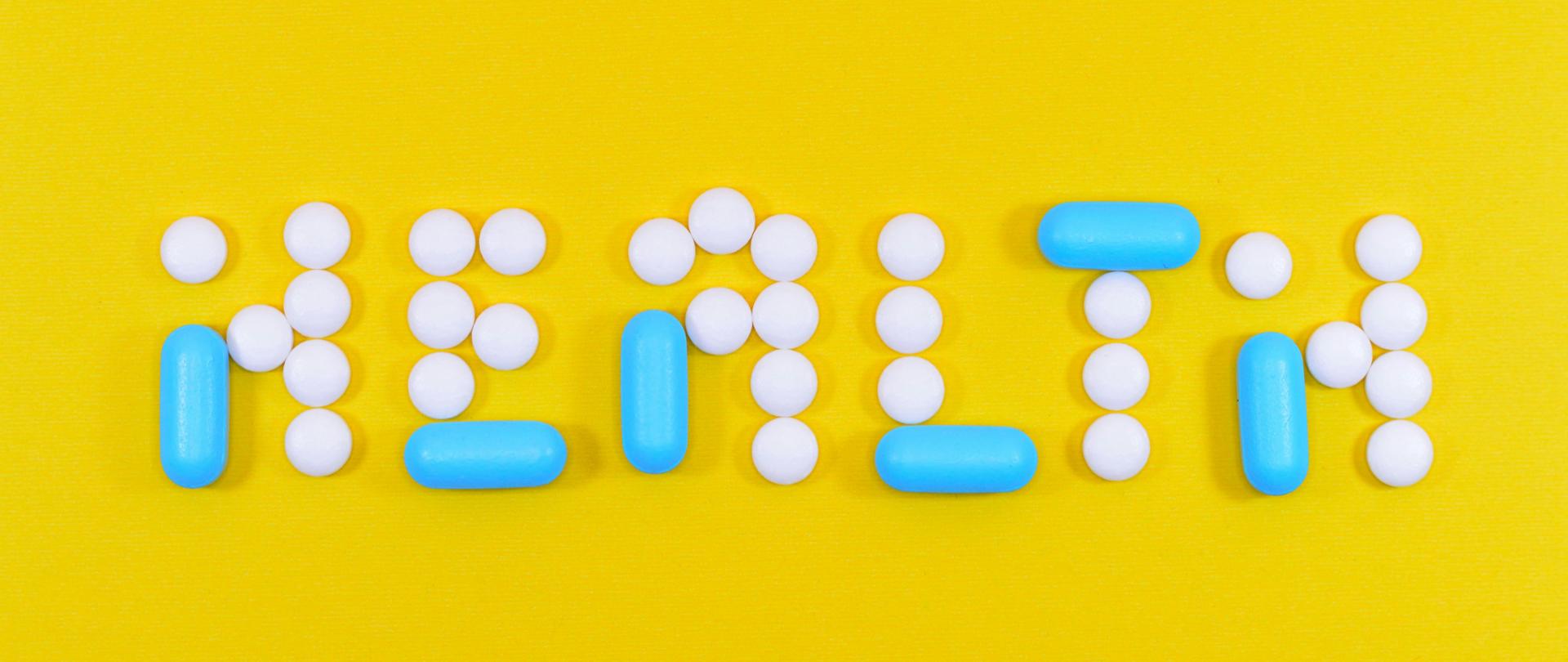 Zdrowie - słowo ułożone z tabletek na żółtym tle