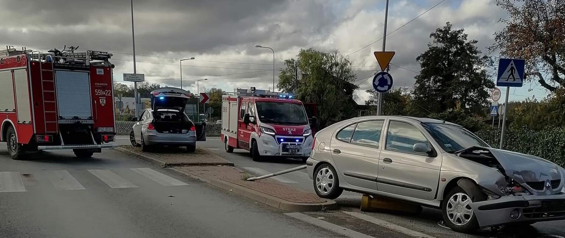 Po lewej widać dwa samochody strażackie i radiowóz Policji, po prawej jest uszkodzony samochód osobowy od przodu