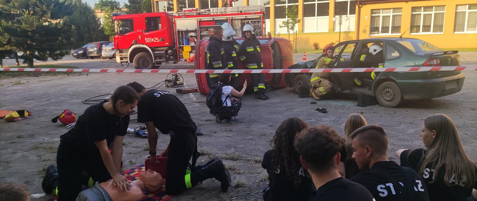 Zdjęcie przedstawia symulowany wypadek drogowy, strażaków podczas uwalniania osoby poszkodowanej oraz uczniów ZS RCKU w Przemystce
