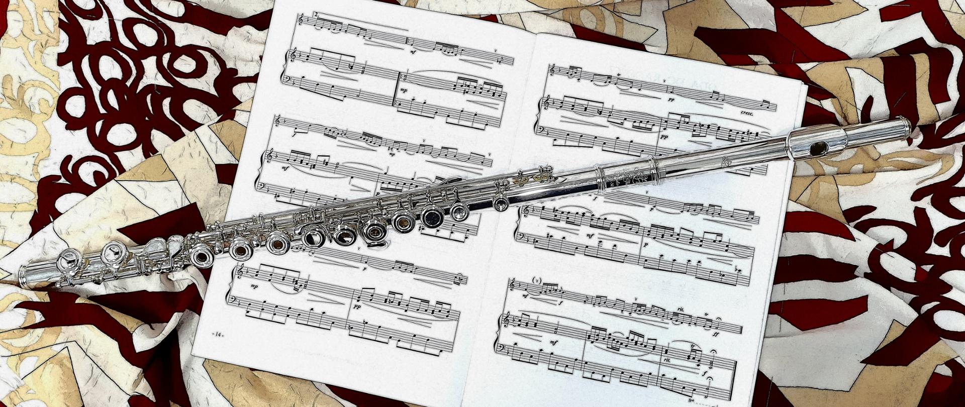 na kolorowym tle umieszczono otwarte nuty a na nim flet.