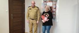 Zdjęcie przedstawia po Komendanta Powiatowego PSP w Rypinie mł. kpt. Marcin Czarneckiego przekazuąacego Pani Joannie Marchlewskiej głównej księgowej list gratulacyjny