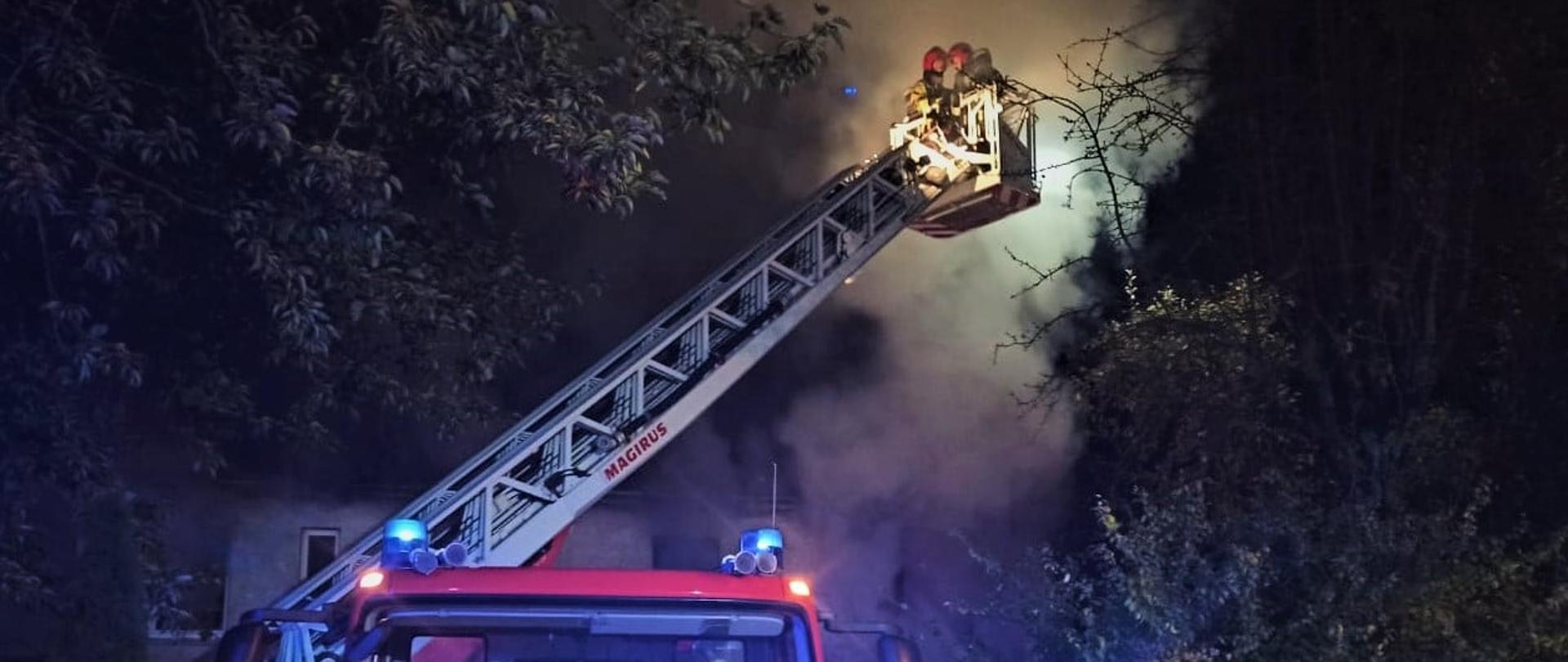 Zdjęcie przedstawia samochód specjalny drabinę z wysuniętym koszem, z którego gaszą ratownicy.