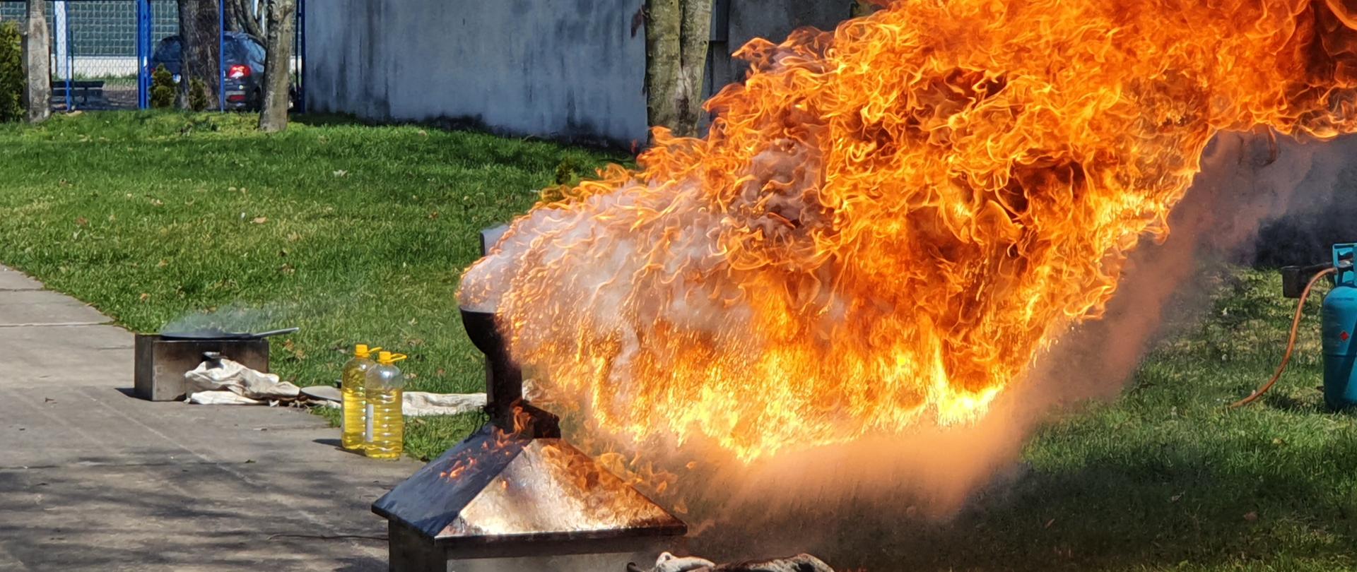 Na zdjęciu widoczny jest płomień sięgający ok. 3 metrów. Jest to moment dolania wody do rozgrzanego oleju, będącego w misie trenażera pożarowego.