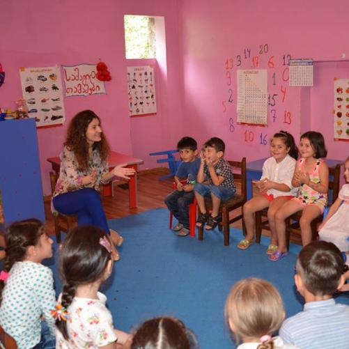 Przedszkolanka i grupa dzieci siedząca w kółku