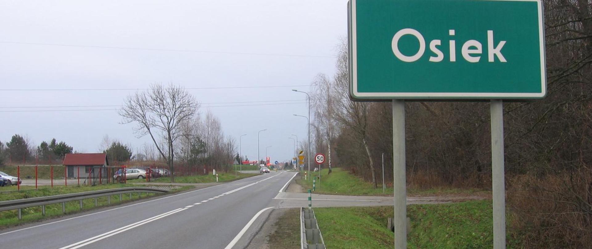 DK79 Osiek - jednojezdniowa droga i tablica z nazwą miejscowości 