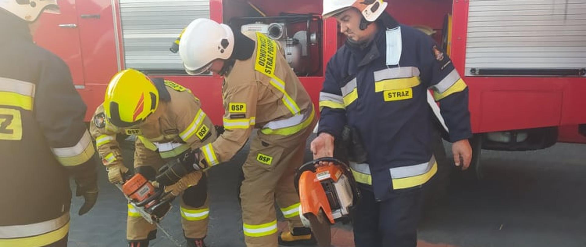 Plac przed remizą OSP Sobiałkowo. Na nim średni samochód ratowniczo - gaśniczy. Przed autem czterech strażaków. Dwóch z nich w rękach trzyma sprzęt tnący.