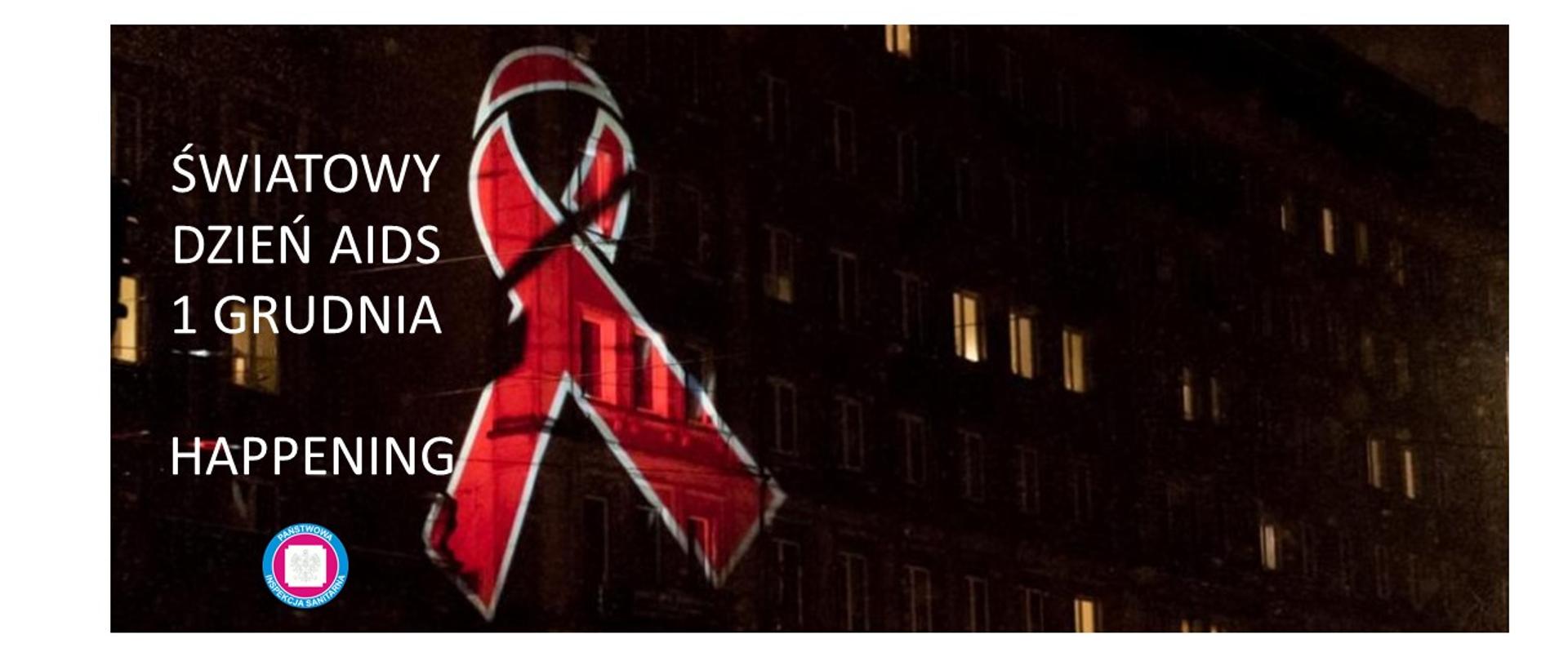 Na zdjęciu jest noc. widać blok w którym świecą się światła. Na budynku projekcja czerwonej wstążki symbolu solidarności z osobami HIV/AIDS