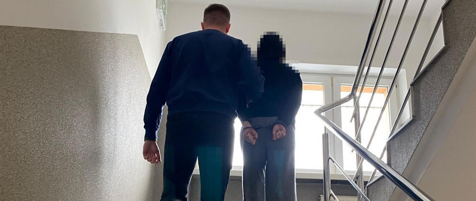 Mężczyzna prowadzi kobietę w kajdankach