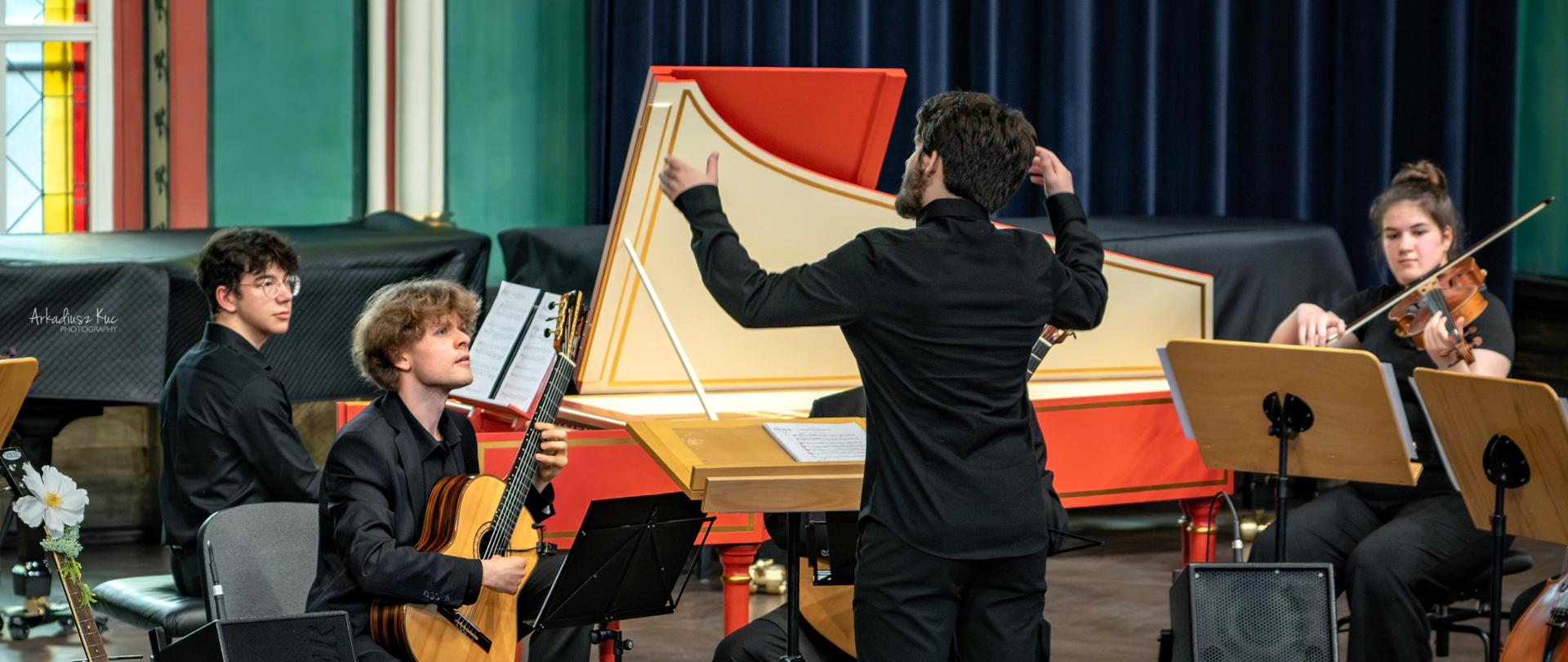 Koncert gitarowy w sali koncertowej szkoły muzycznej w Bytomiu. Na scenie gitarzysta na tle orkiestry