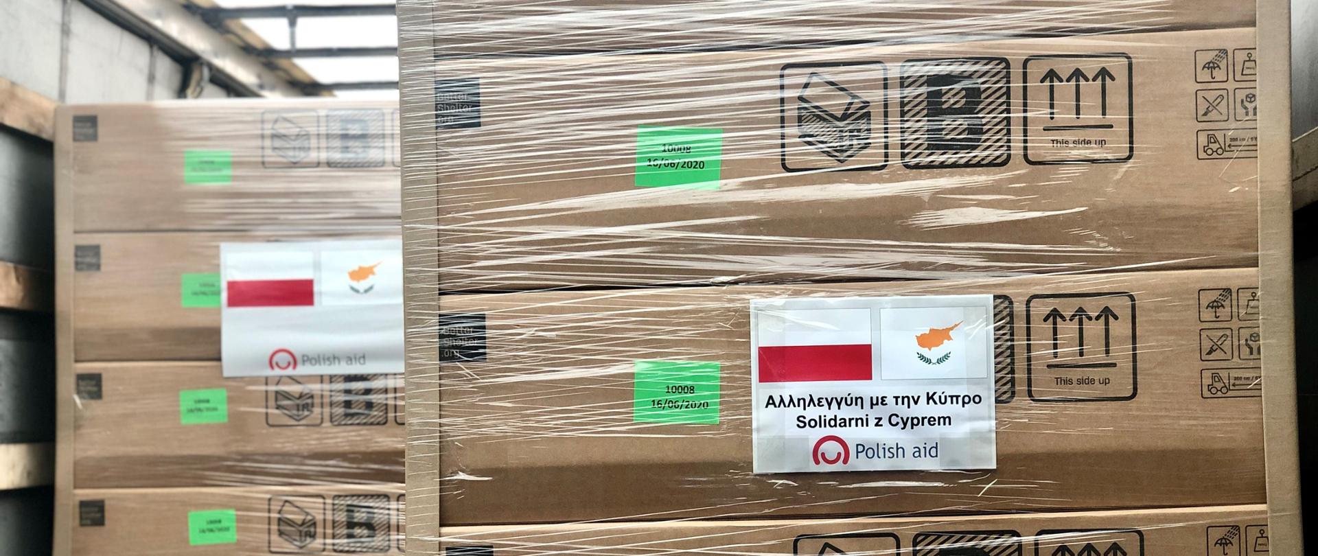 paczki zapakowane oklejone flagą Polski i Cypru oraz napisem w języku greckim Solidarni z Cyprem.