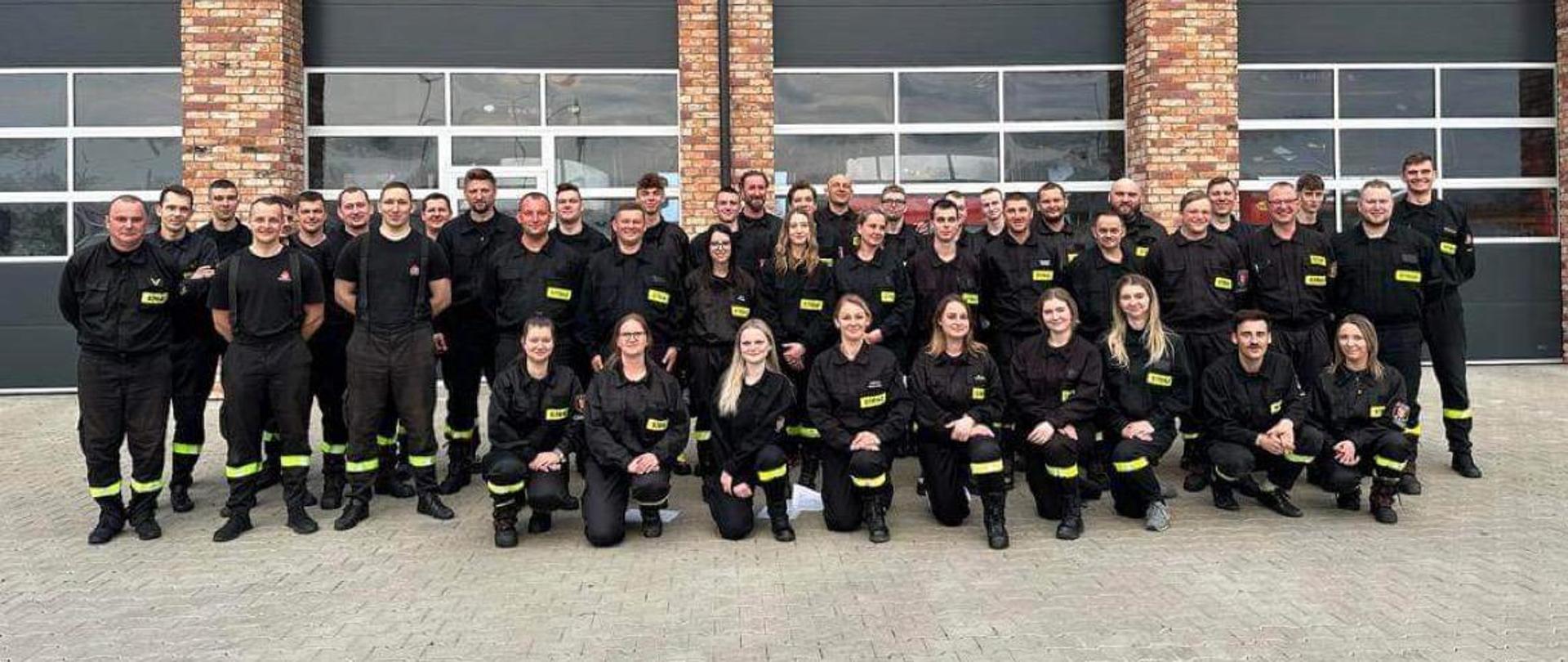 Przed budynkiem Komendy Powiatowej Państwowej Straży Pożarnej w Świeciu pozują do zdjęcia uczestnicy egzaminu na zakończenie szkolenia podstawowego strażaków ratowników Ochotniczej Straży Pożarnej. 