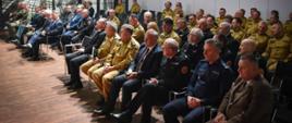 uczestnicy narady siedzący na krzesłach w sali konferencyjnej, część z nich to strażacy w umundurowaniu służbowym