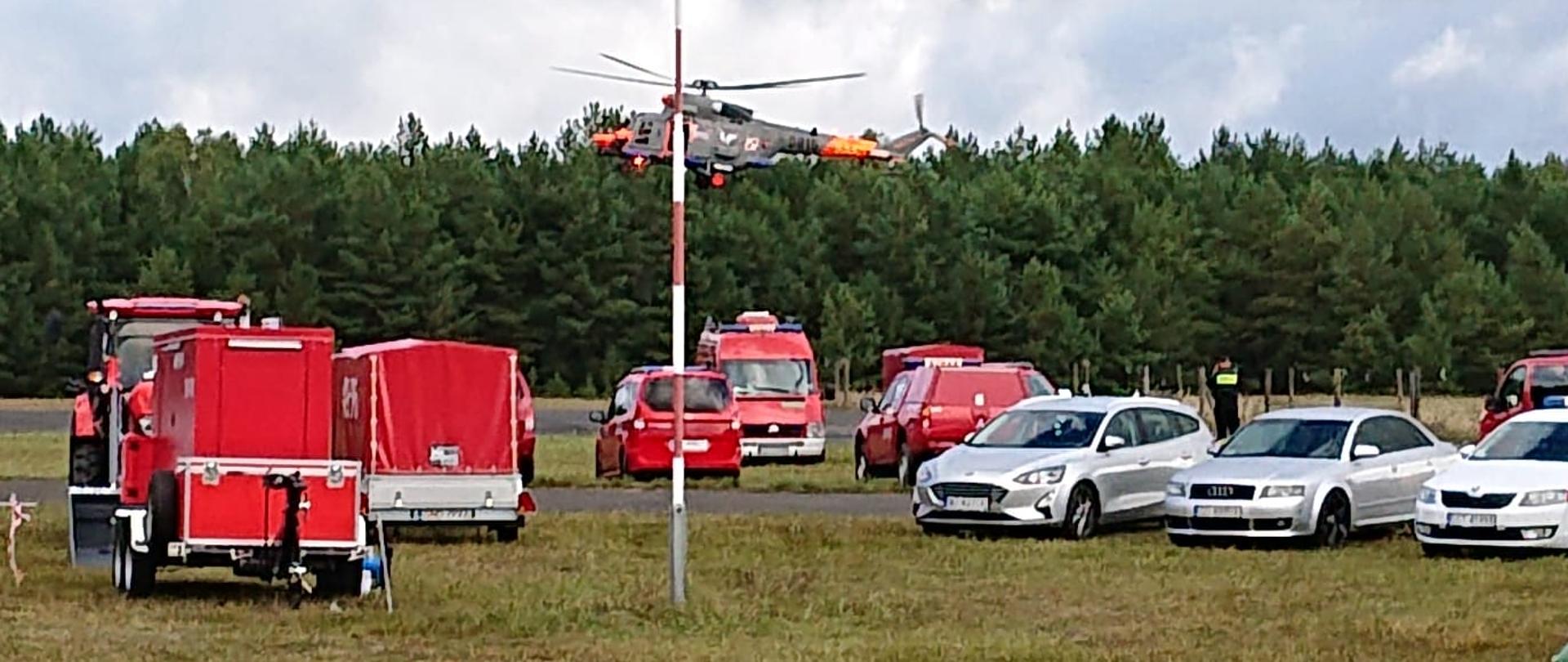 zastępy PSP nad którymi unosi się śmigłowiec. W tle widać las