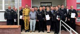 Strażacy pozują do fotografii przed budynkiem 