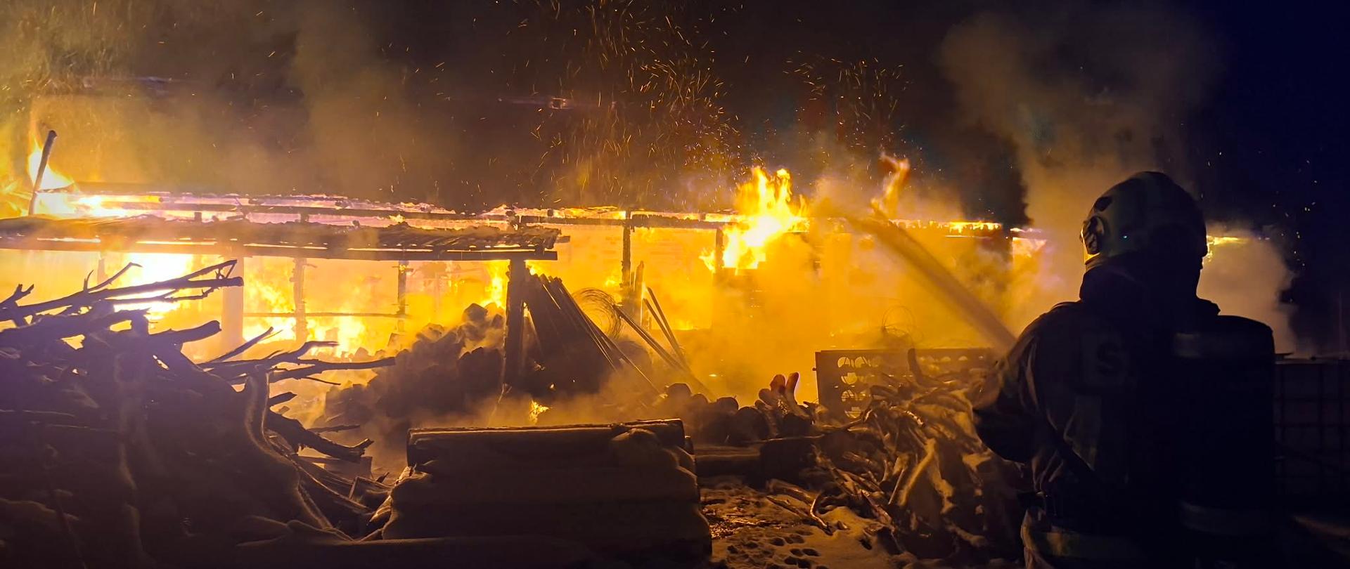 Pali się budynek gospodarczy, widać ogień, jest noc