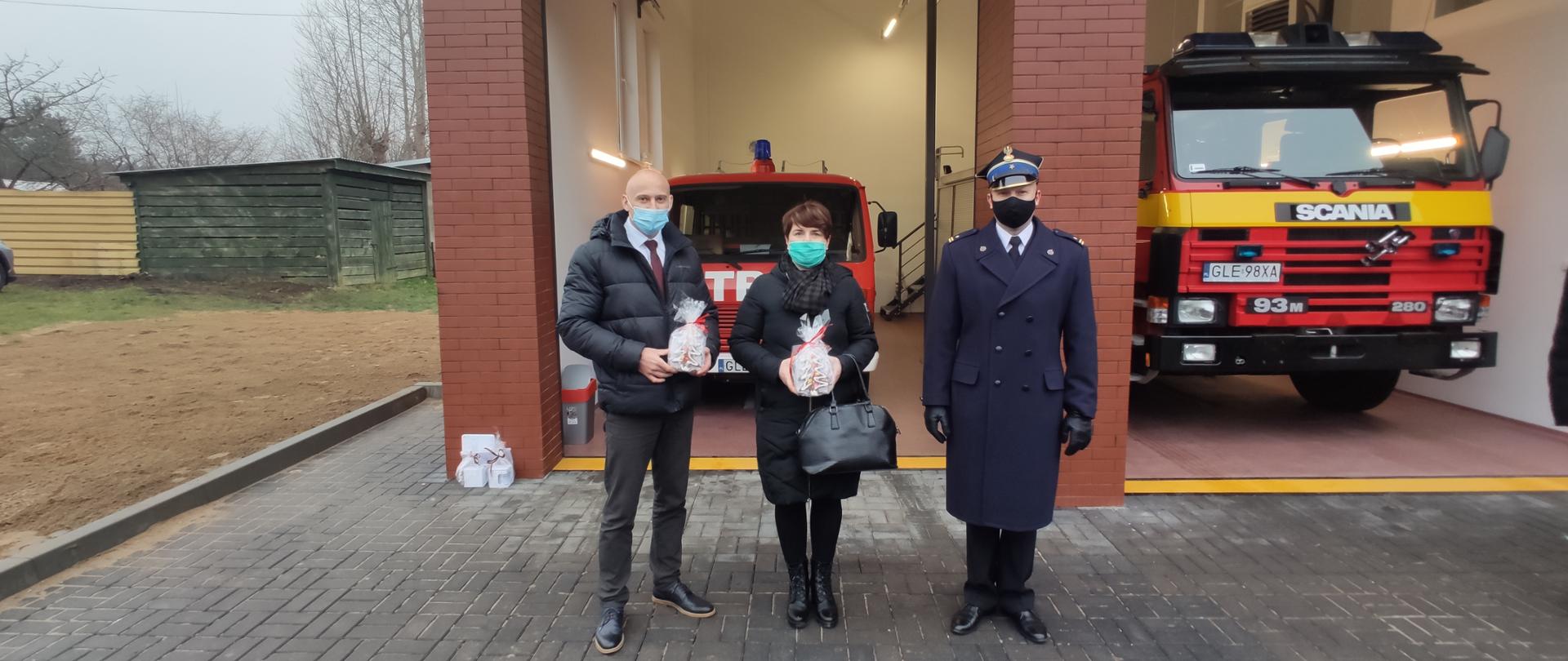 Delegacja trzech osób na tle garaży nowo-otwartej remizy złożona z (od lewej: Wójt Gminy Wicko, Zastępca Wójta Gminy Wicko, Komendant Powiatowy Państwowej Straży Pożarnej w Lęborku) 