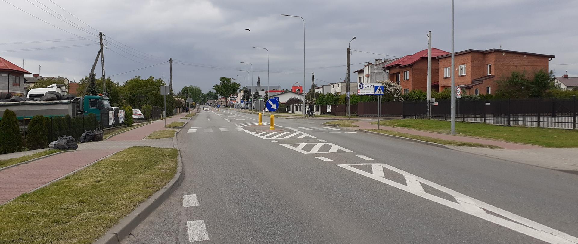 Ulica przebiegająca przez niedużą miejscowość, po obu stronach budynki