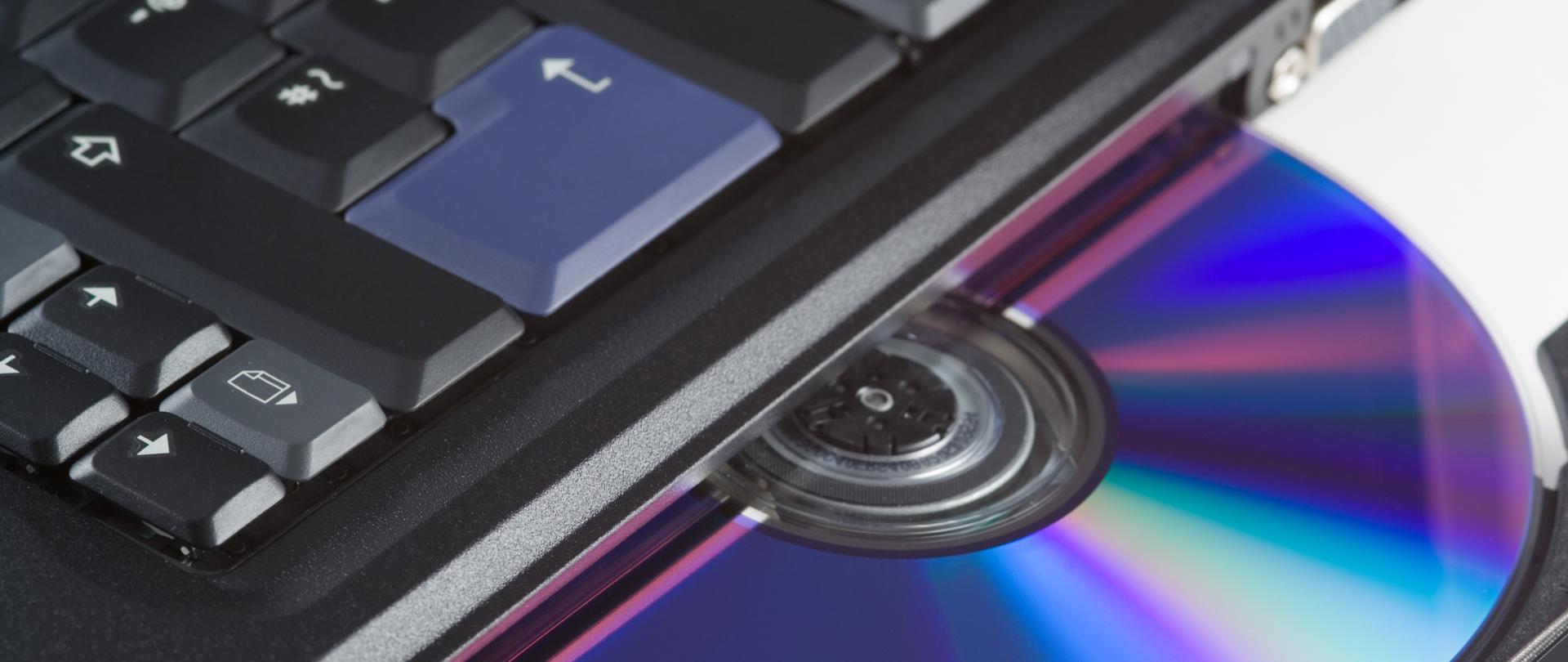 Laptop z płytą DVD leżącą na tacce napędu