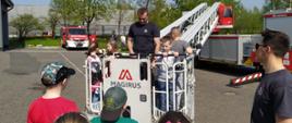 Na zdjęciu strażacy prezentują dzieciom drabinę mechaniczną