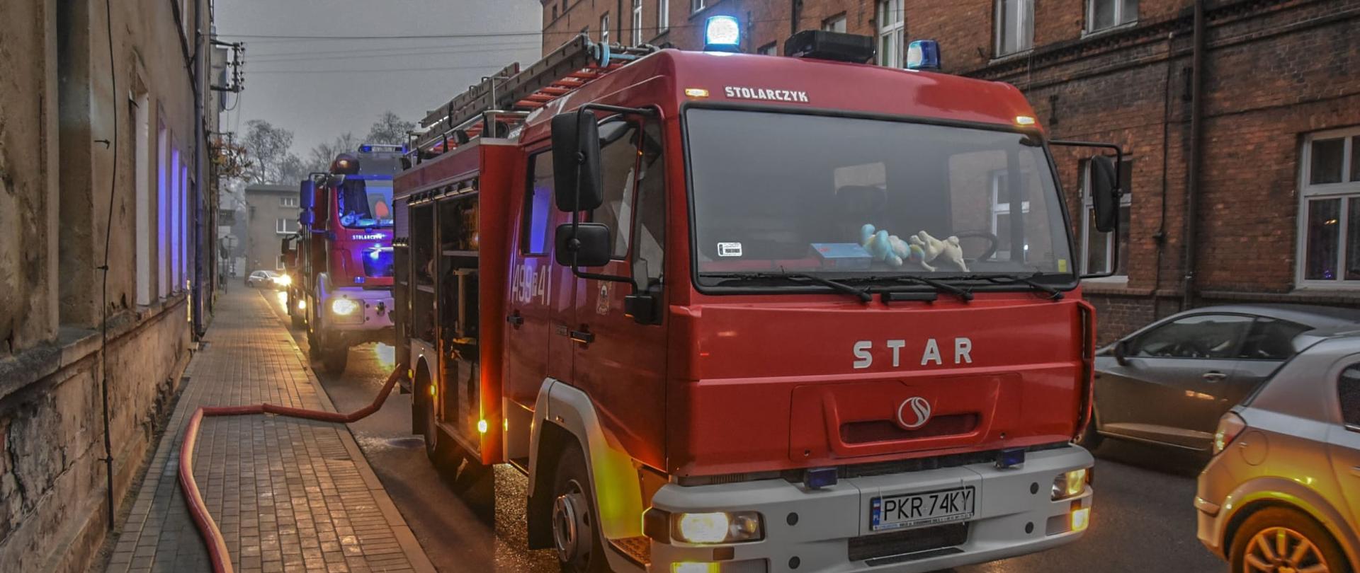 Zdjęcie przedstawia trzy samochody pożarnicze stojące na jednym pasie drogi. Z pierwszego wozu wyprowadzona jest linia główna służąca do zabezpieczenia działań ratowniczo-gaśniczych. 