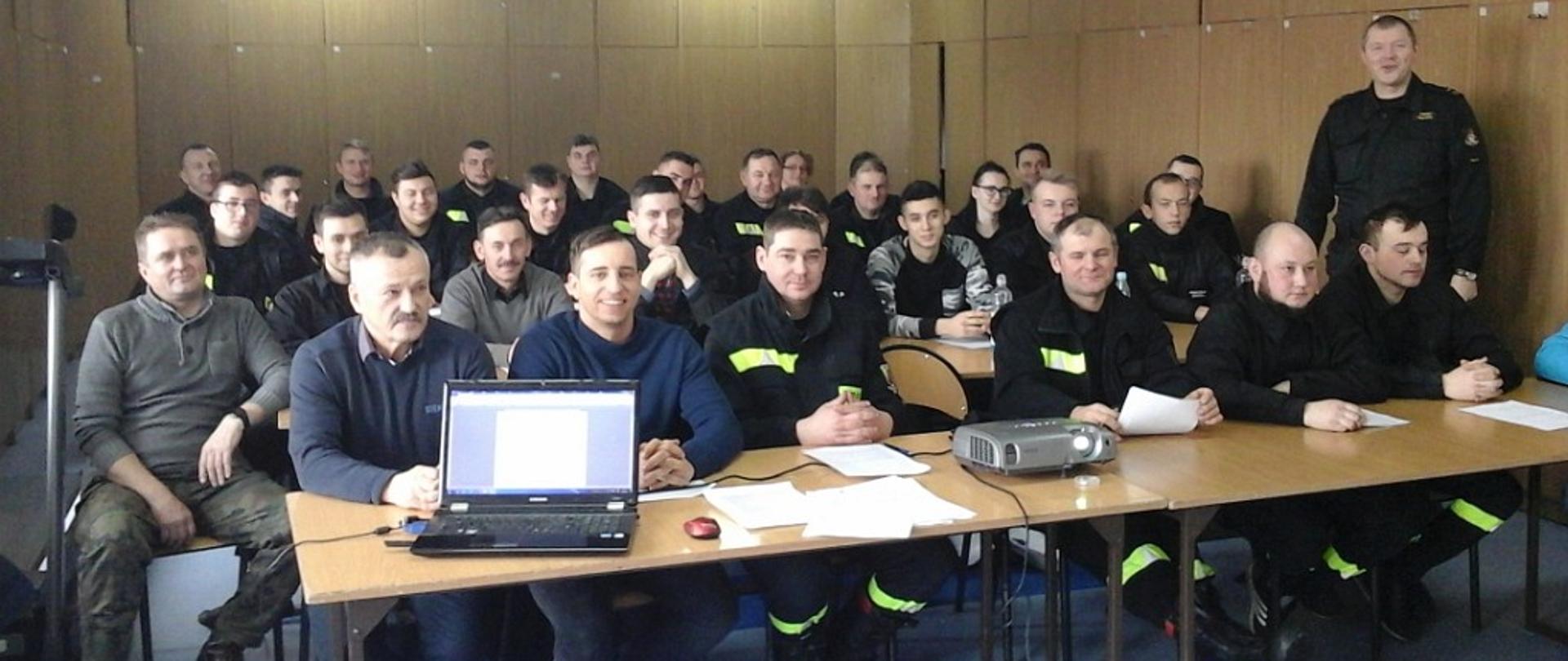 Na zdjęciu widać strażaków OSP siedzących w ławkach, uczestniczących w szkoleniu OSP