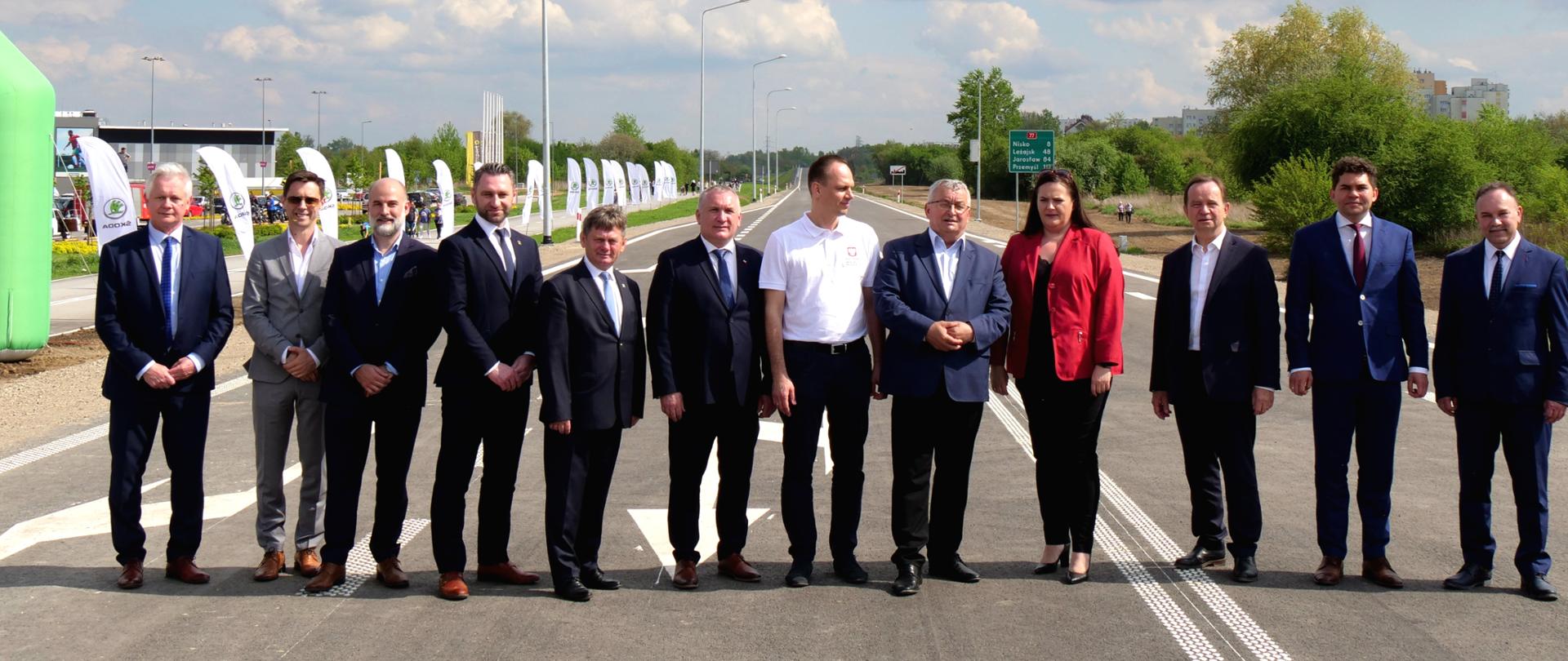 W poprzek drogi w rzędzie stoi grupa ludzi. Wśród nich wiceminister Małgorzata Jarosińska-Jedynak.