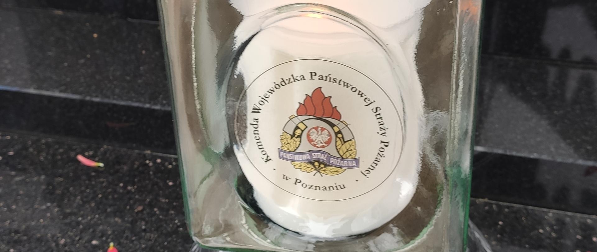 Znicz przeźroczysty z logo Państwowej Straży Pożarnej na czarnej płycie