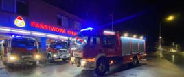 Zdjęcie wykonane w porze nocnej. Widać nowy pojazd ratowniczo-gaśniczy w kolorze czerwonym. Stoi na kostce brukowej przed garażami JRG 1 Kalisz.